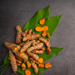 Article: Natural Chicken Health Remedies. Pic - Turmeric roots on a green leaf against a grey stone background.